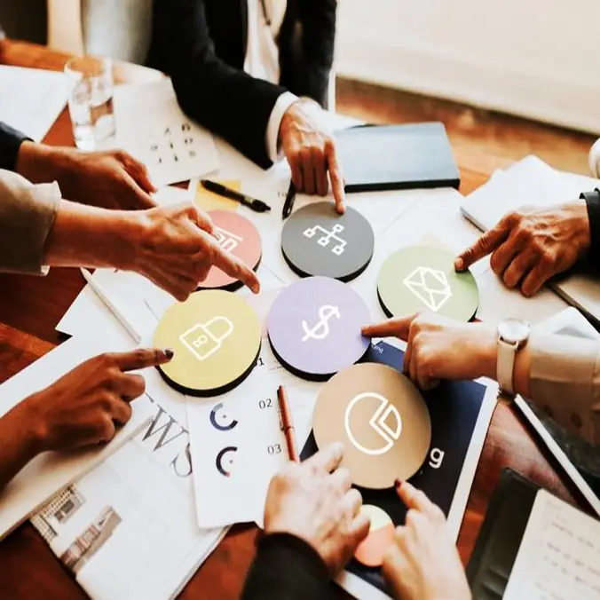 Team members arranging business icons on a table